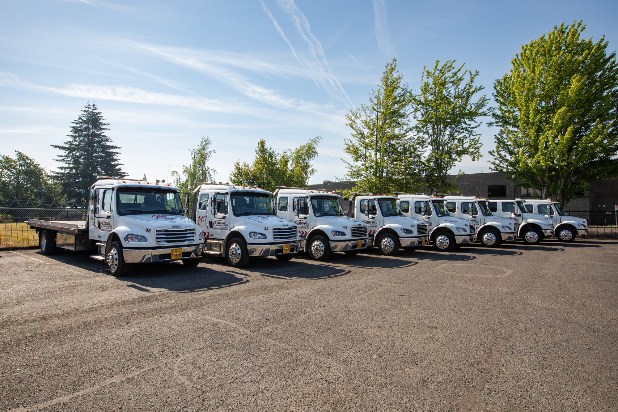 Crown Towing & Repair AAA-branded flatbed tow truck fleet lined up at the SE Portland yard
