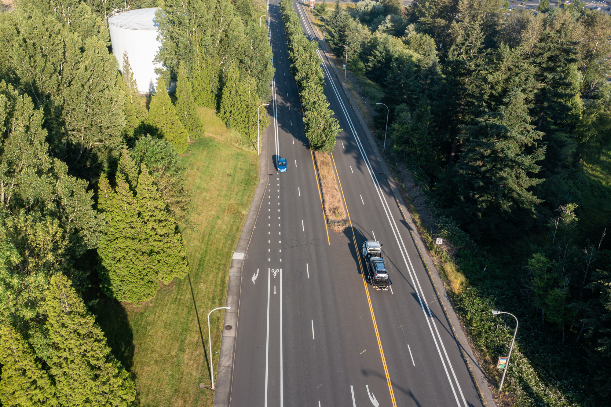 Aerial view of a Crown flatbed tow truck transporting a customer vehicle on a Portland-area highway