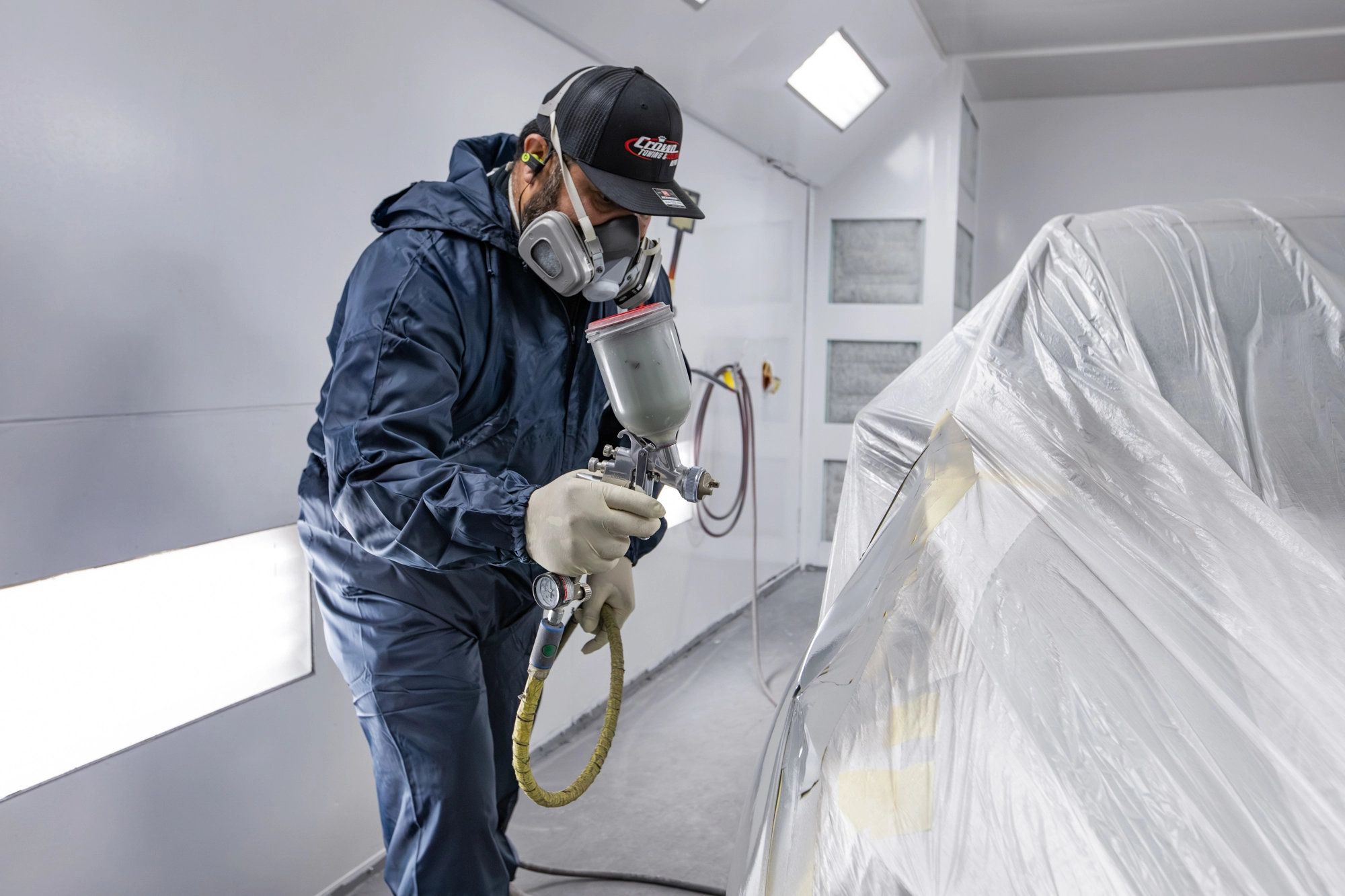 Crown painter applying finish coats inside the downdraft paint booth in Portland
