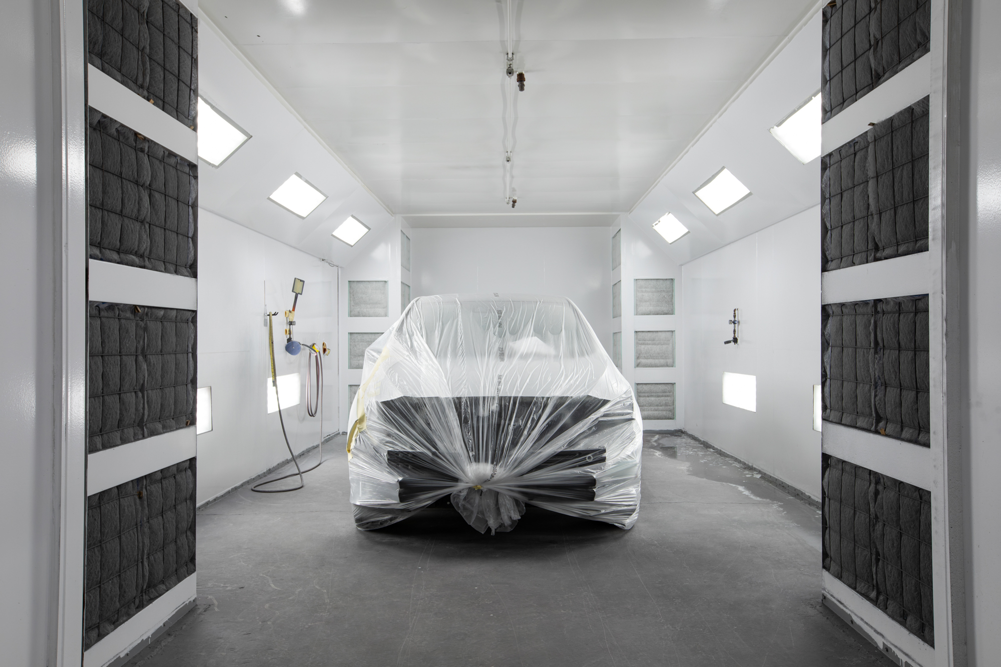 Customer vehicle masked and covered inside Crown's downdraft paint booth ready for refinishing