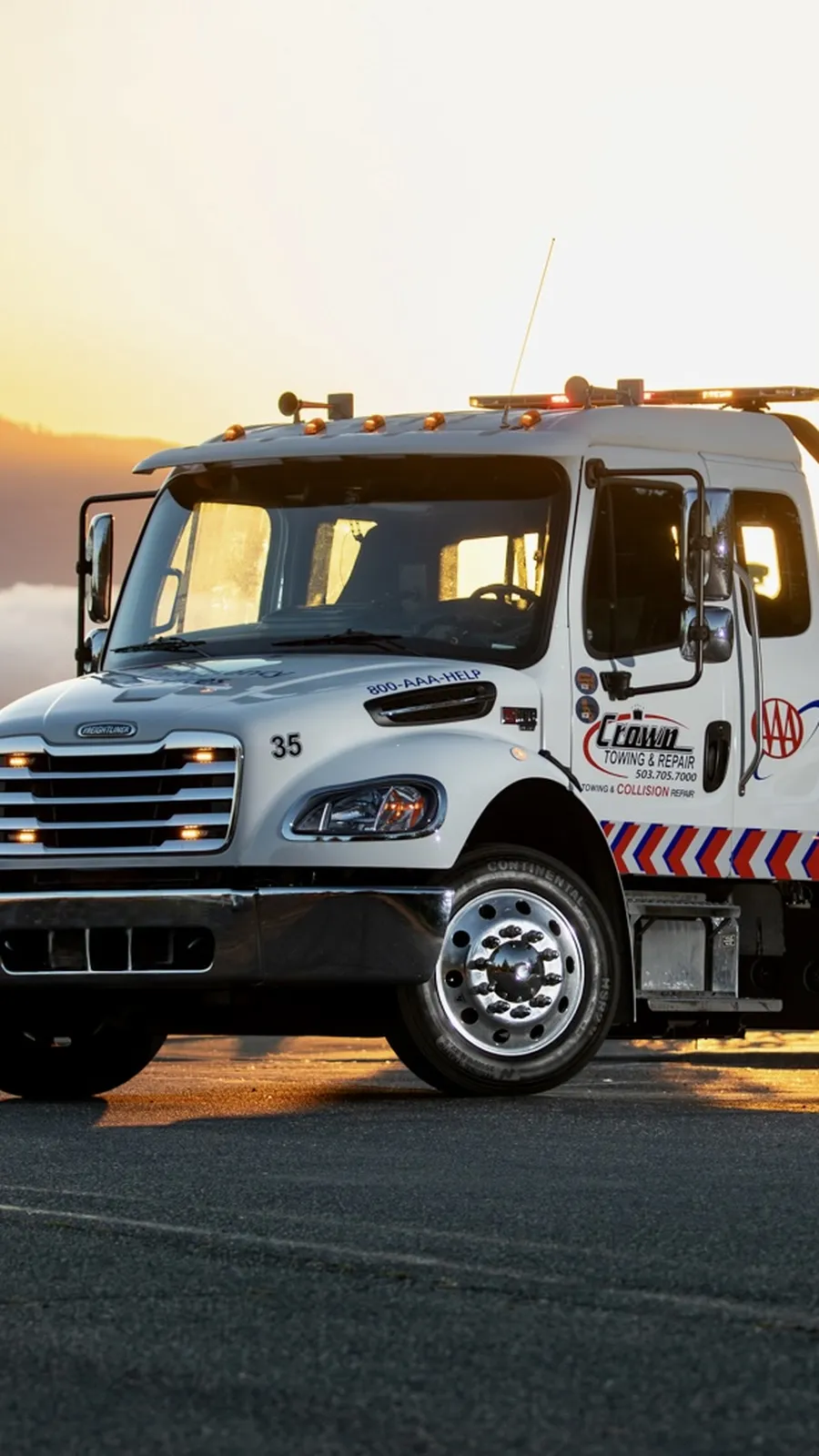 Crown Towing flatbed tow truck carrying a red sports car at sunset in the Columbia River Gorge