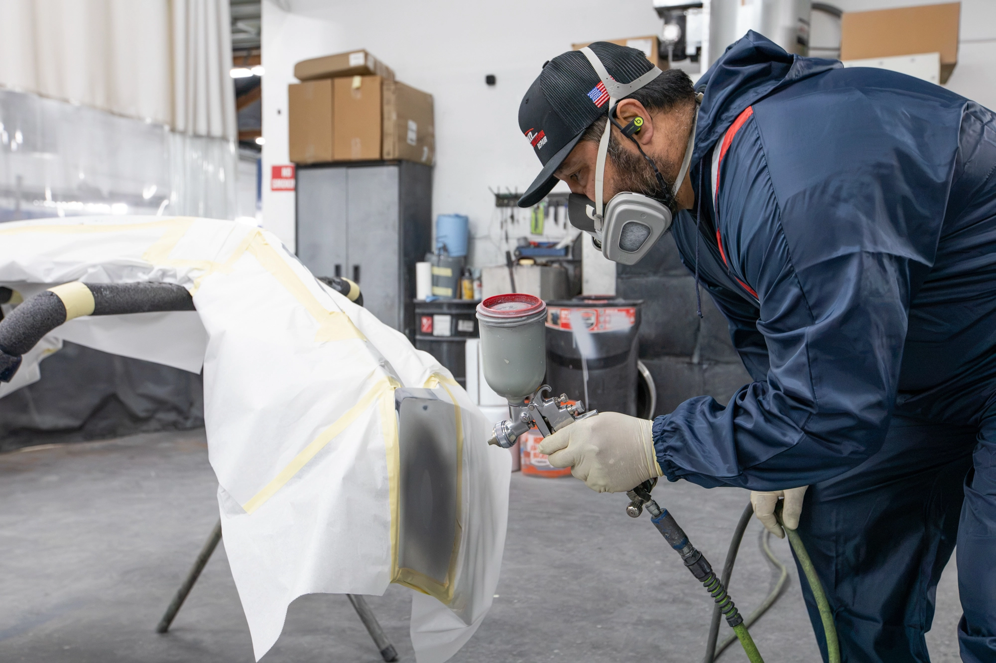 Crown refinishing technician spraying a repaired bumper cover in the Portland shop