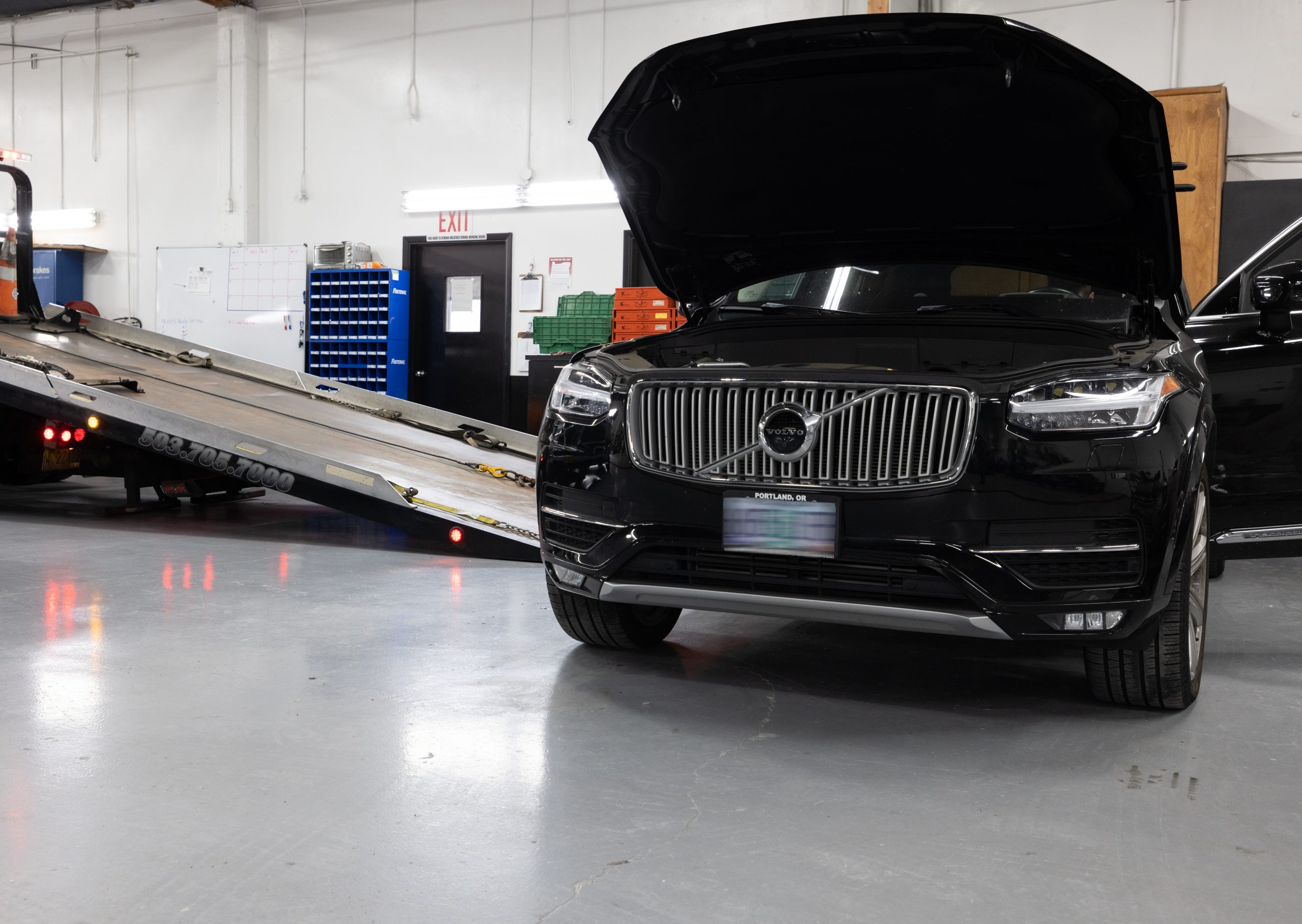 Crown tow truck operator securing a customer vehicle to the flatbed for transport